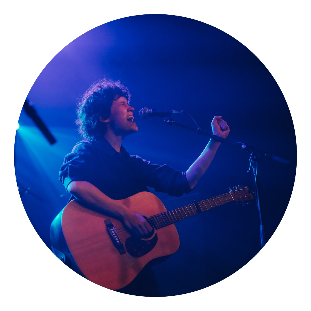 S LaJoye singing in front of mic holding a guitar